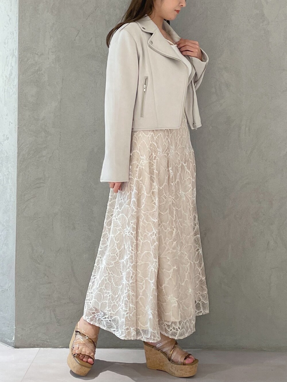 ブラウン系のサンダル、ホワイト系のニット/セーター、ホワイト系のライダースジャケットを着用したレディースの春コーディネートの3枚目の写真