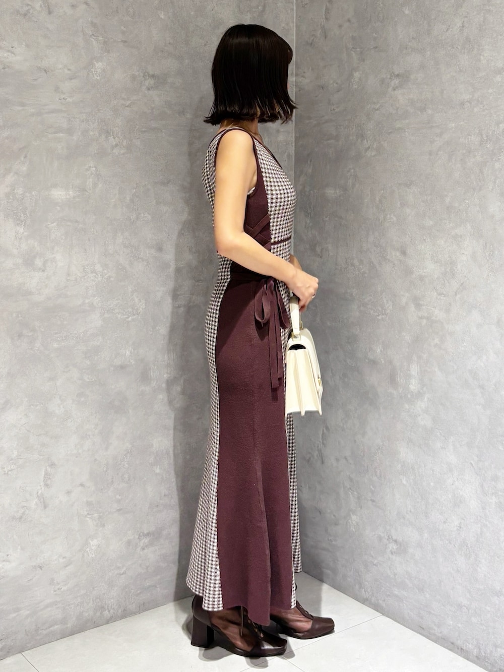 ブラウン系のワンピース、ブラウン系のブーツ、ホワイト系のハンドバッグを着用したレディースの夏コーディネートの3枚目の写真