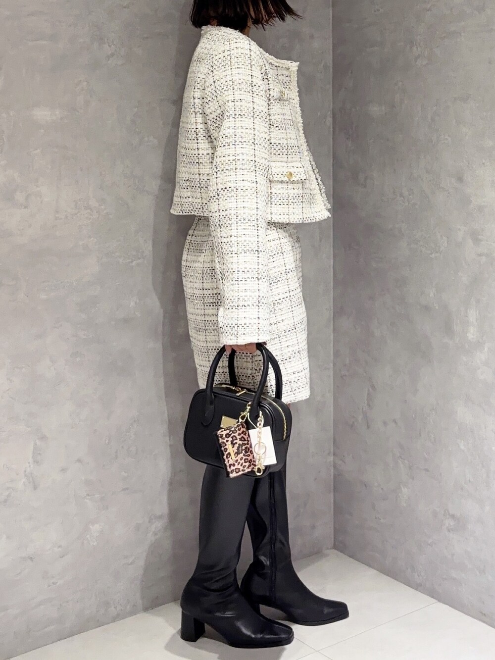 ホワイト系のスカート、ブラック系のブーツ、ブラック系のハンドバッグを着用したレディースの秋コーディネートの4枚目の写真