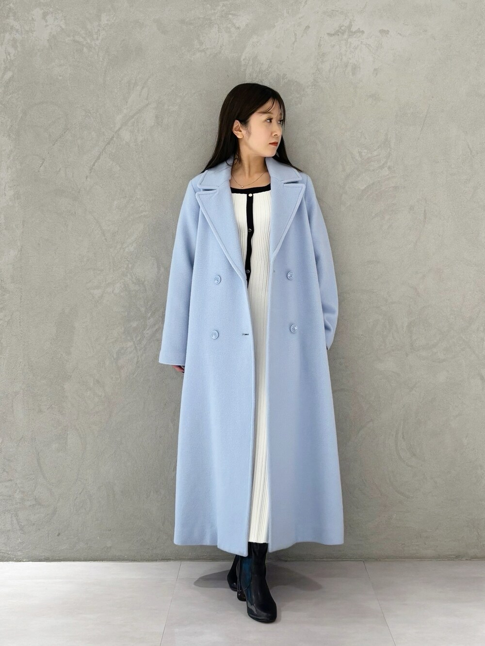 ブルー系のチェスターコート、ブラック系のブーツ、ホワイト系のワンピースを着用したレディースの冬コーディネートの7枚目の写真