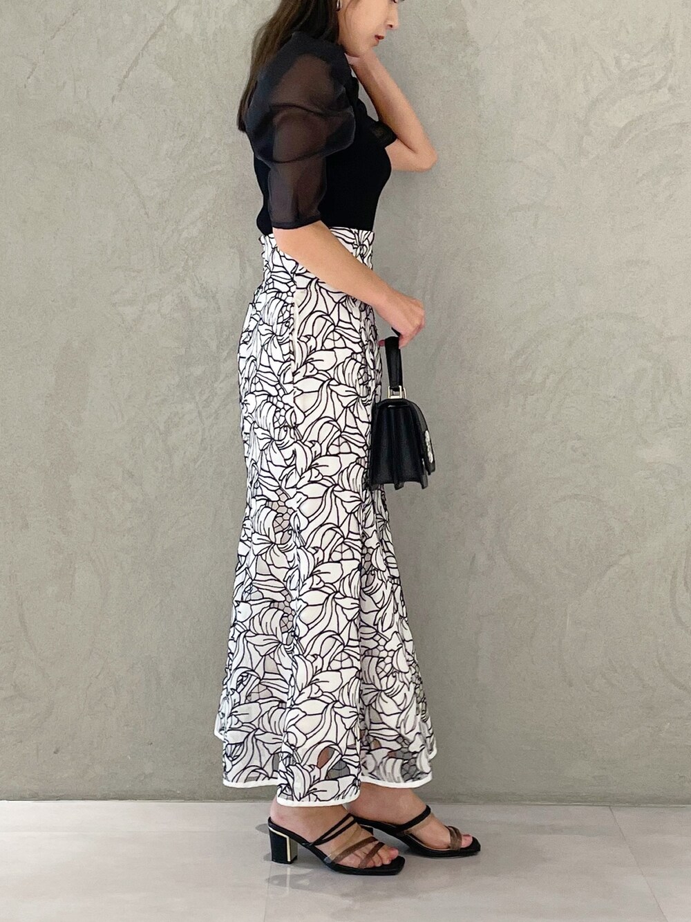 ホワイト系のスカート、ブラック系のサンダル、ブラック系のショルダーバッグを着用したレディースの夏コーディネートの3枚目の写真