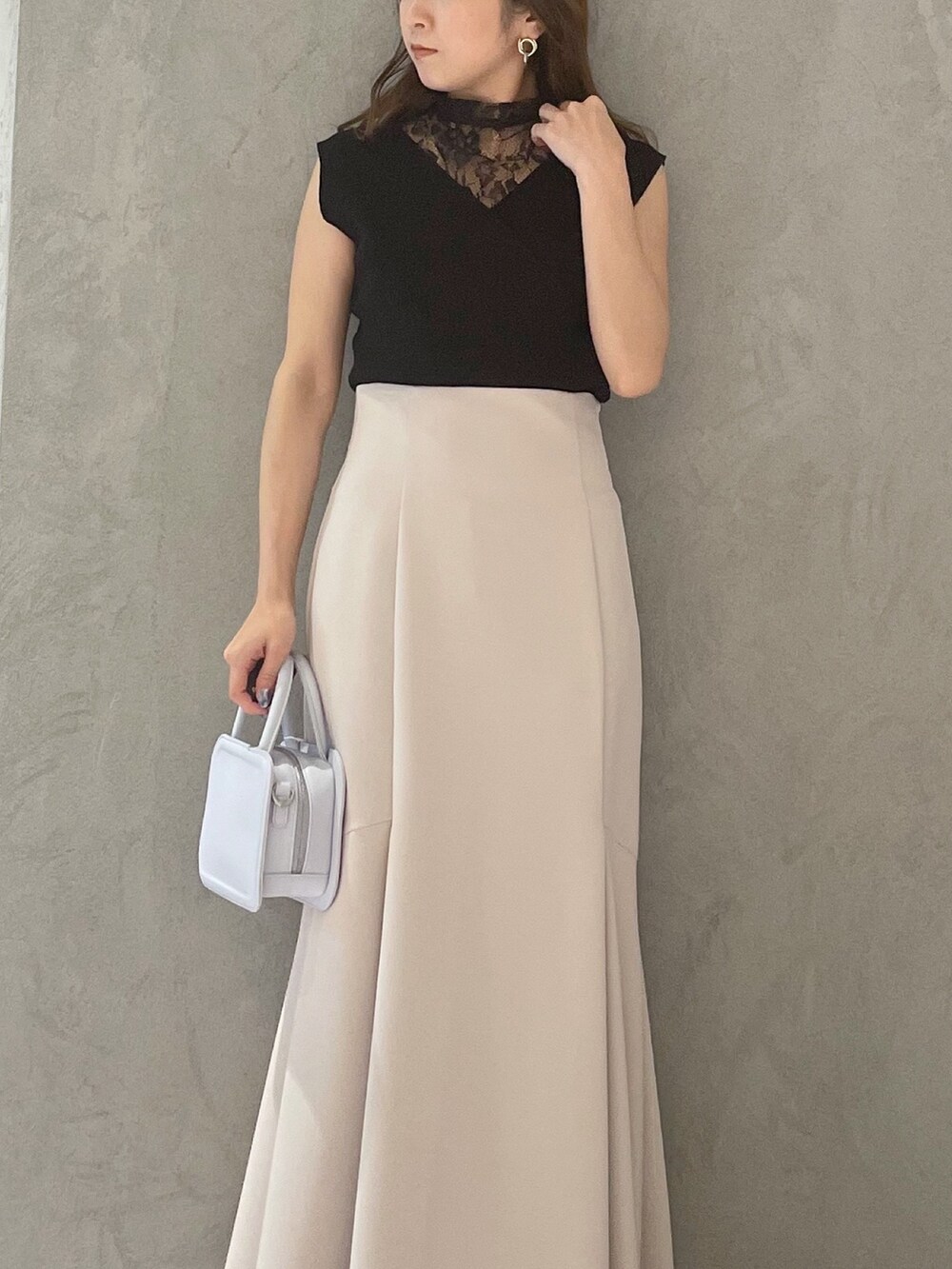 ブルー系のハンドバッグ、ブラック系のサンダル、ベージュ系のスカートを着用したレディースの春コーディネートの3枚目の写真