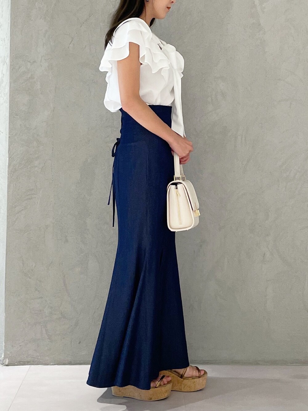 ブルー系のスカート、ブラウン系のサンダル、ホワイト系のショルダーバッグを着用したレディースの夏コーディネートの3枚目の写真