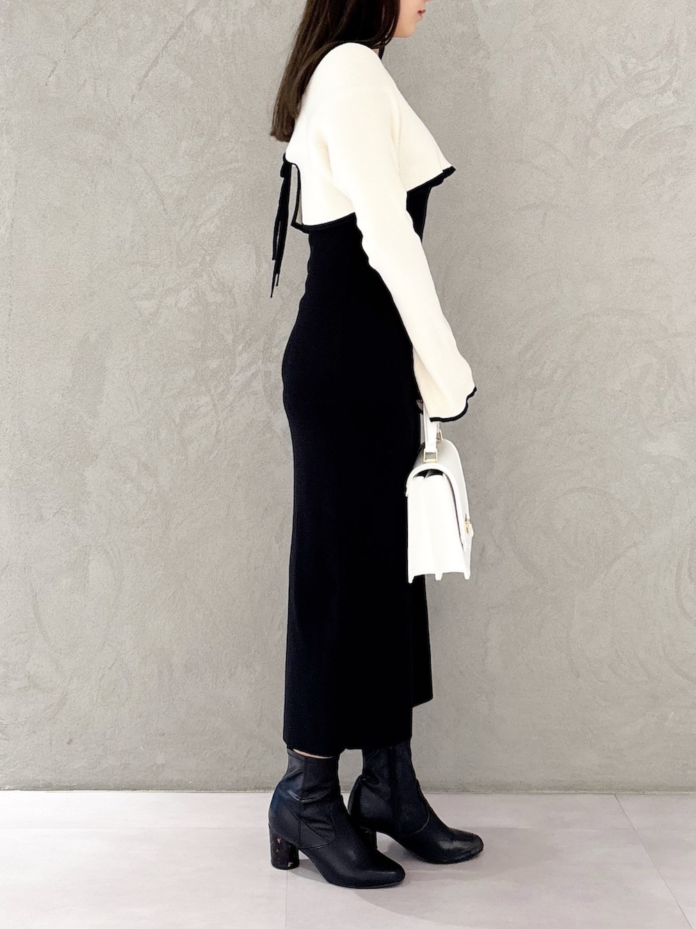 ブラック系のブーツ、ホワイト系のハンドバッグ、ブラック系のワンピースを着用したレディースの冬コーディネートの2枚目の写真