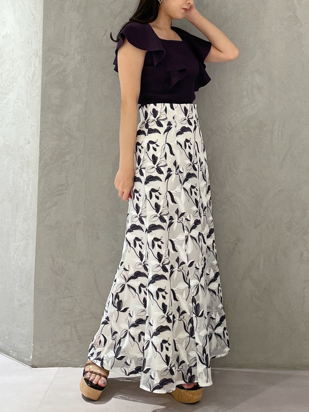 ホワイト系のスカート、グレー系のニット/セーター、ブラック系のサンダルを着用したレディースの春コーディネートの3枚目の写真