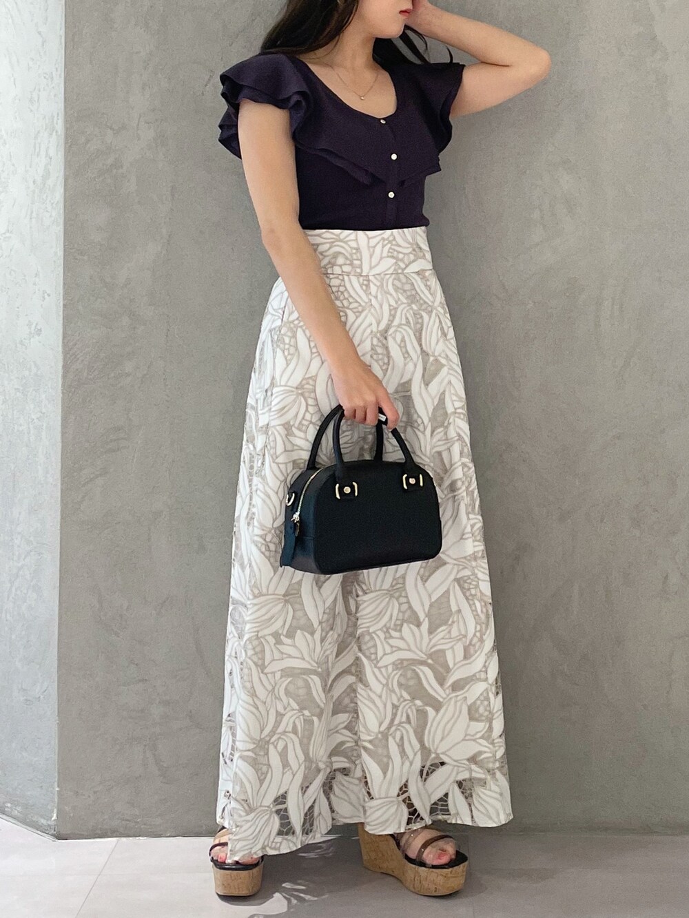 ブラック系のサンダル、ブラック系のボストンバッグ、ホワイト系のスカートを着用したレディースの春コーディネートの2枚目の写真