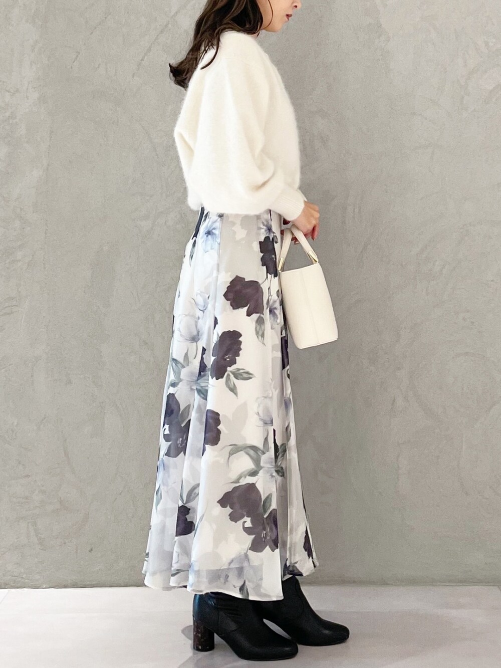 ホワイト系のハンドバッグ、ブラック系のブーツ、ブルー系のスカートを着用したレディースの秋コーディネートの4枚目の写真