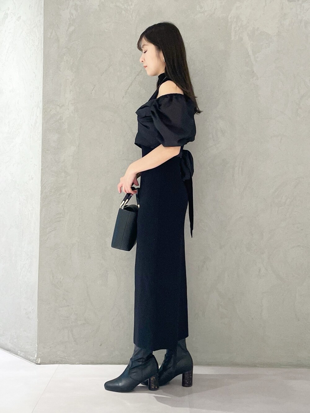 ブラック系のハンドバッグ、ブラック系のブーツ、ブラック系のワンピースを着用したレディースの春コーディネートの4枚目の写真