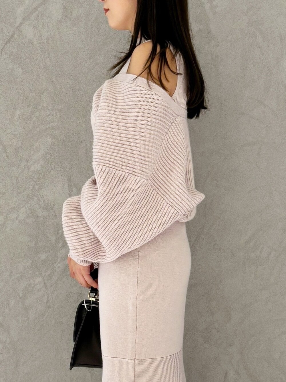 ブラウン系のハンドバッグ、ピンク系のワンピース、ブラック系のブーツを着用したレディースの冬コーディネートの3枚目の写真