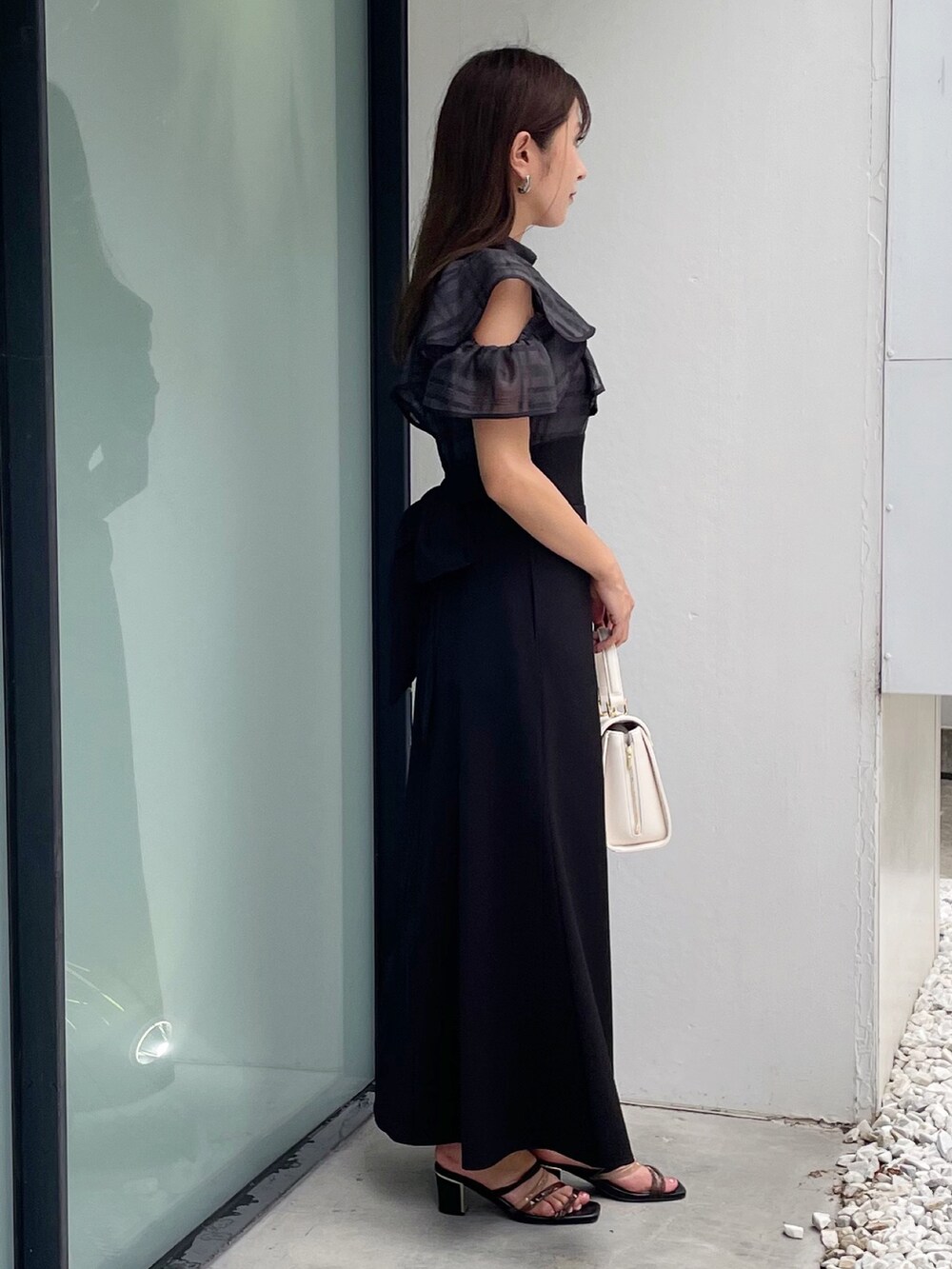 ブラック系のワンピース、ブラック系のサンダル、ホワイト系のショルダーバッグを着用したレディースの夏コーディネートの6枚目の写真