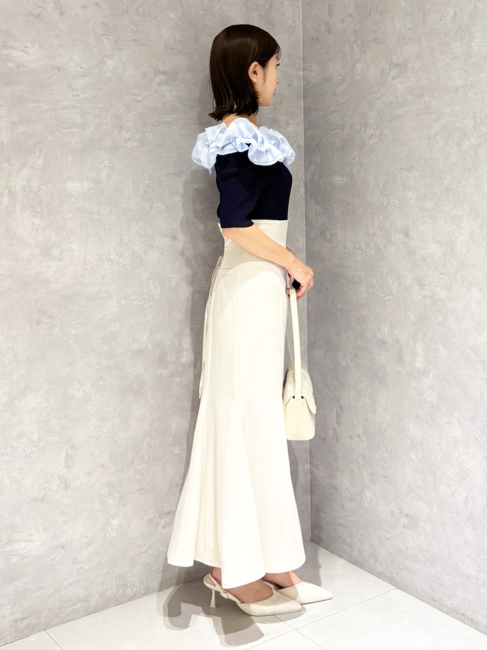 ホワイト系のスカート、ホワイト系のパンプス、ブルー系のニット/セーターを着用したレディースの春コーディネートの2枚目の写真