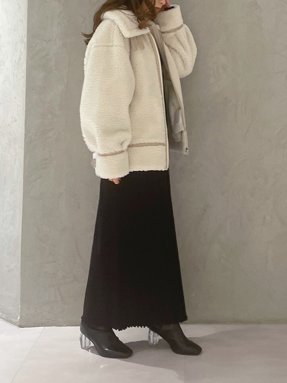 ブラック系のワンピース、ホワイト系のその他アウター、ブラック系のブーツを着用したレディースの冬コーディネートの5枚目の写真