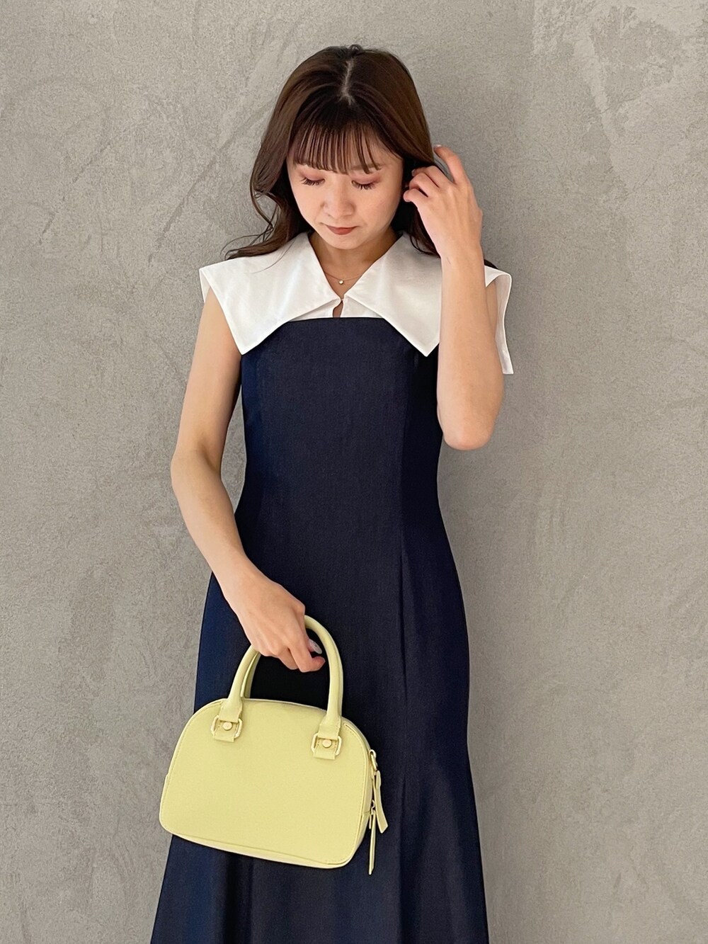 ブルー系のワンピース、イエロー系のボストンバッグ、ブラック系のサンダルを着用したレディースの春コーディネートの2枚目の写真