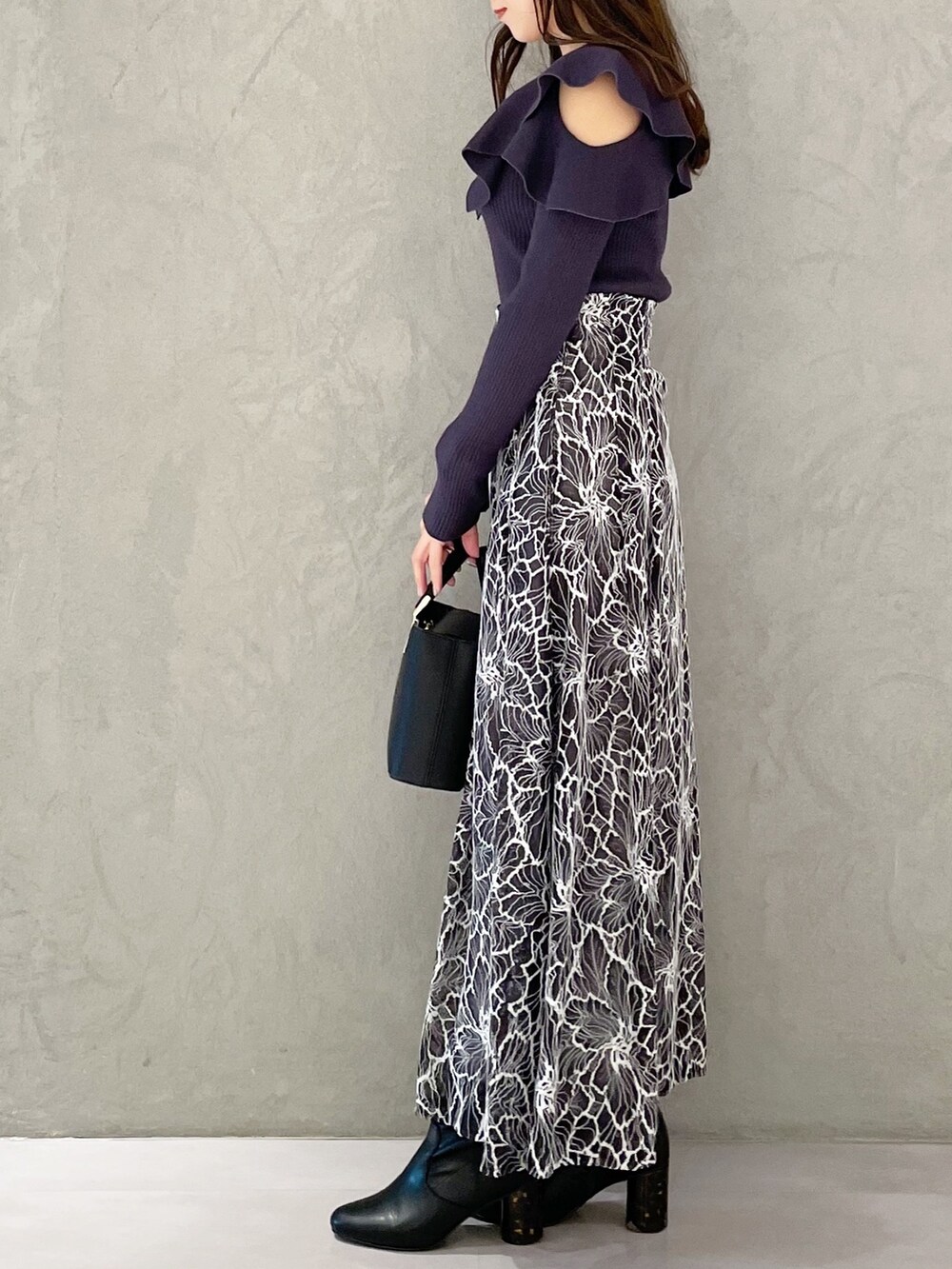 グレー系のスカート、ブラック系のブーツ、ブラック系のハンドバッグを着用したレディースの冬コーディネートの3枚目の写真