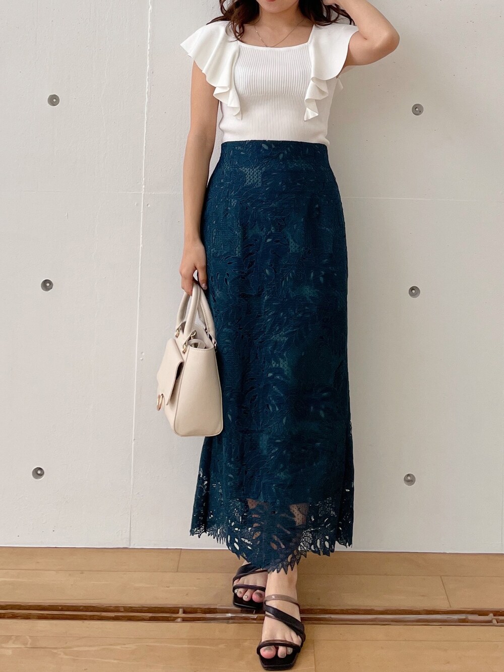 グリーン系のスカート、ブラック系のサンダル、ホワイト系のハンドバッグを着用したレディースの春コーディネートの6枚目の写真