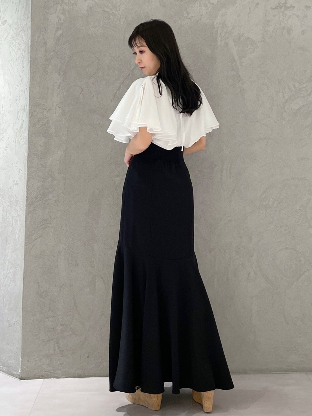 ブラック系のスカート、ブラック系のサンダル、ホワイト系のシャツ/ブラウスを着用したレディースの春コーディネートの4枚目の写真