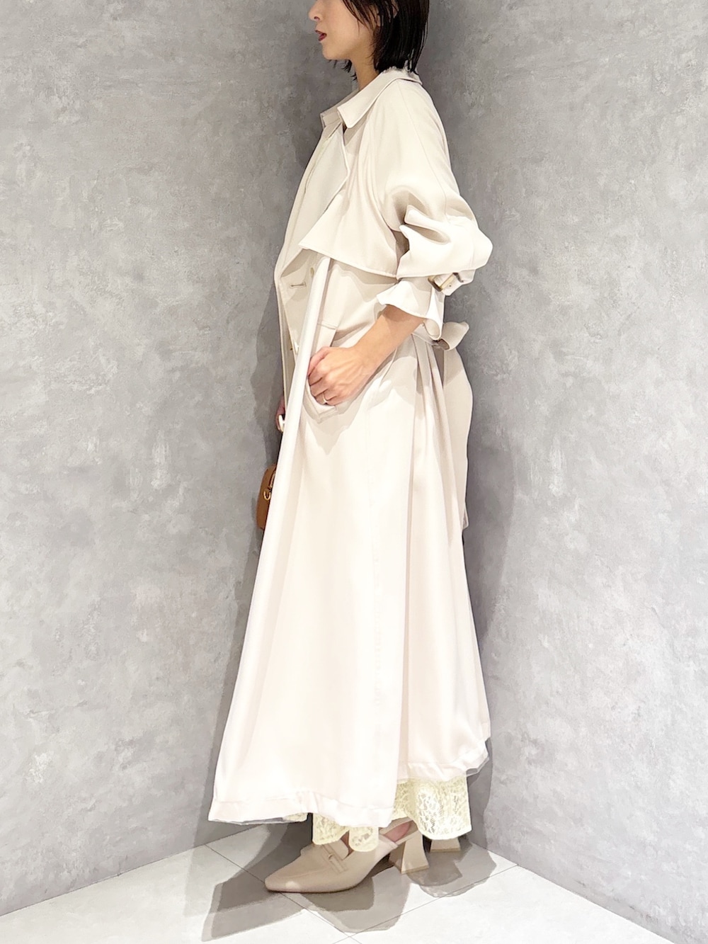 イエロー系のワンピース、ホワイト系のパンプス、ブラウン系のハンドバッグを着用したレディースの春コーディネートの4枚目の写真