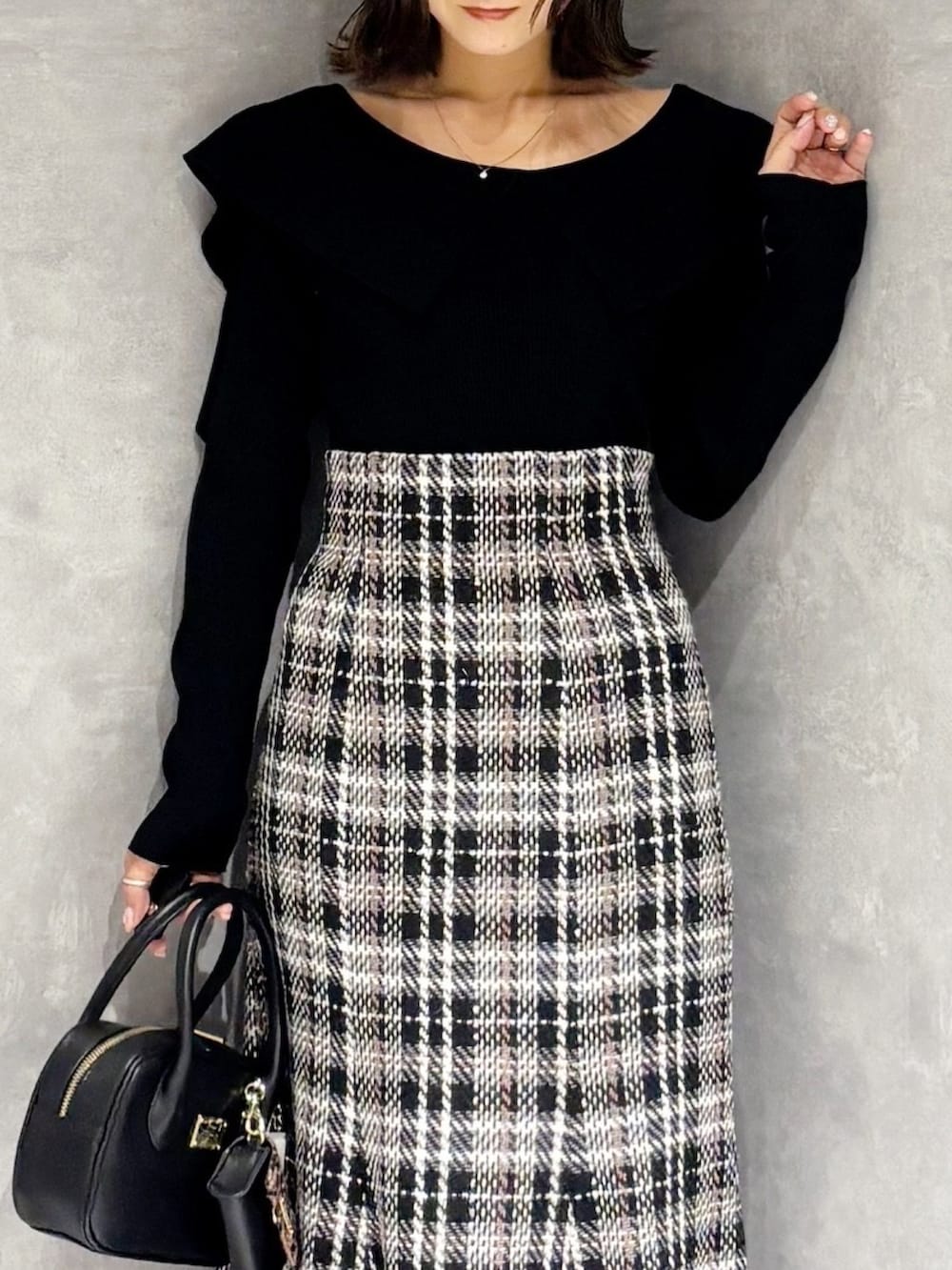 ブラック系のスカート、ブラック系のブーツ、ブラック系のハンドバッグを着用したレディースの秋コーディネートの4枚目の写真