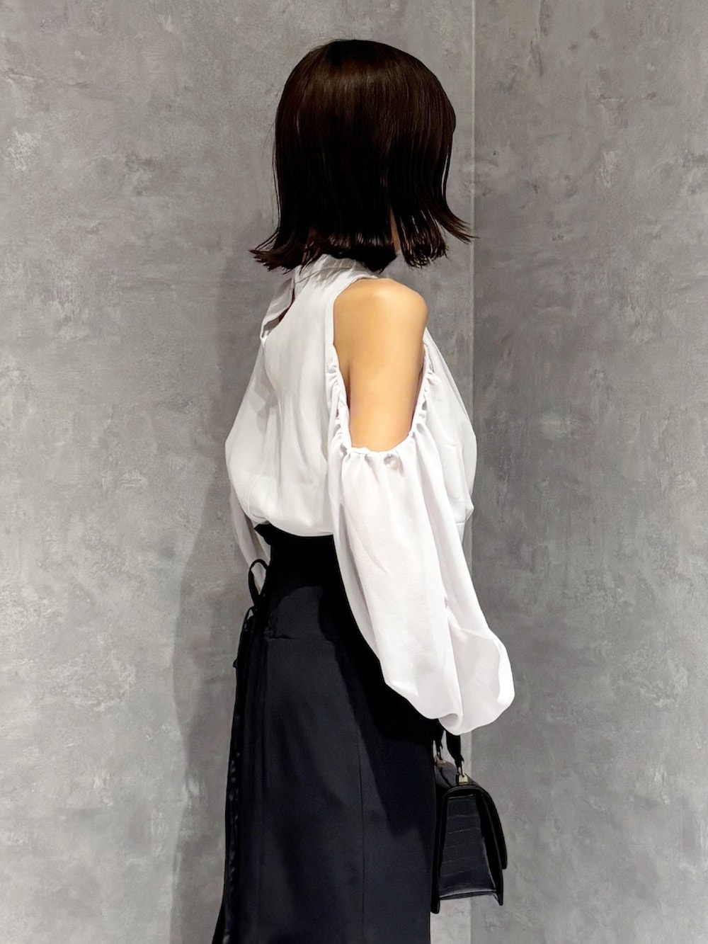 ブラック系のハンドバッグ、ブラック系のブーツ、ブラック系のスカートを着用したレディースの秋コーディネートの5枚目の写真