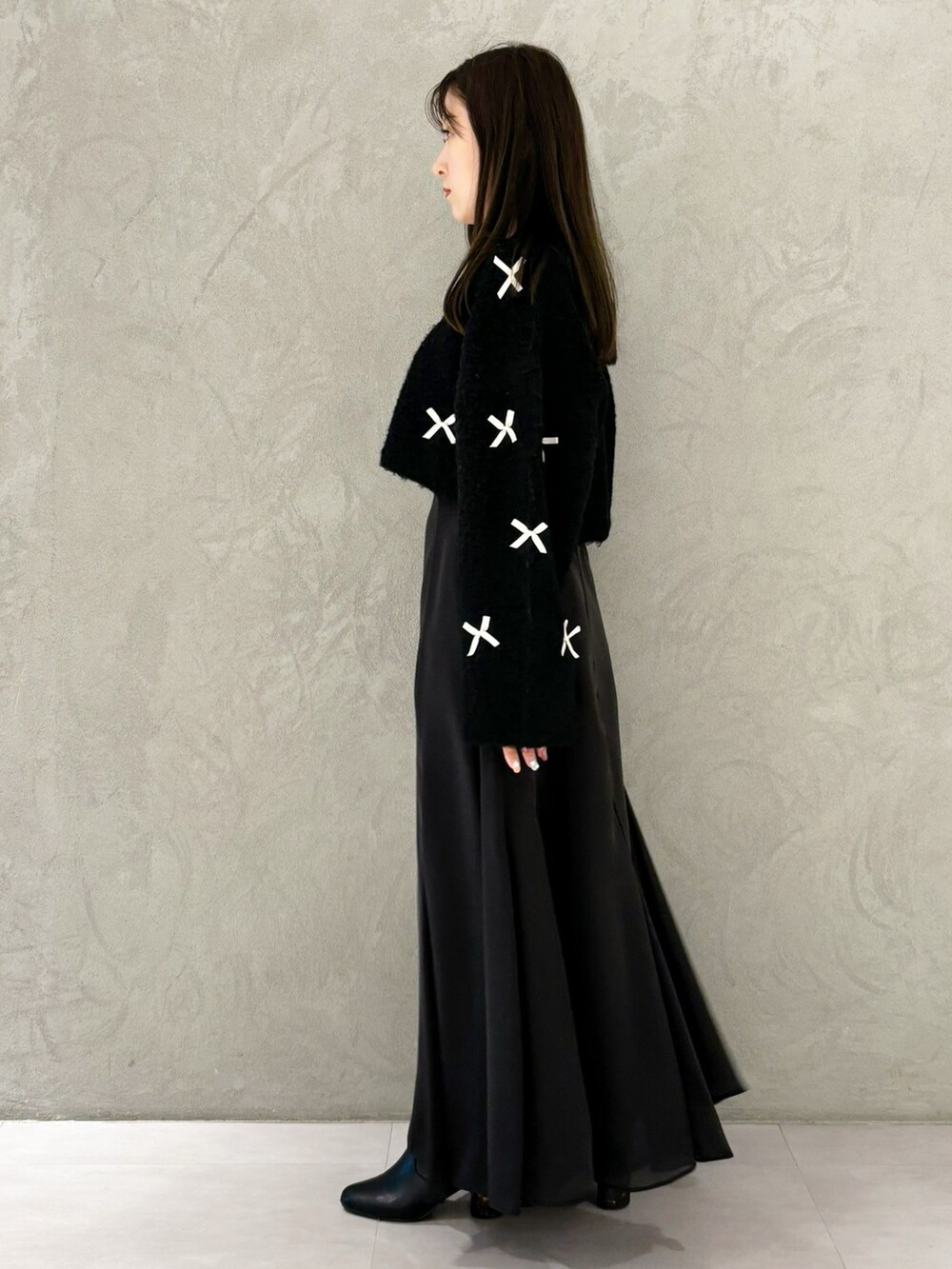 ブラック系のスカート、ブラック系のブーツ、ホワイト系のハンドバッグを着用したレディースの冬コーディネートの5枚目の写真