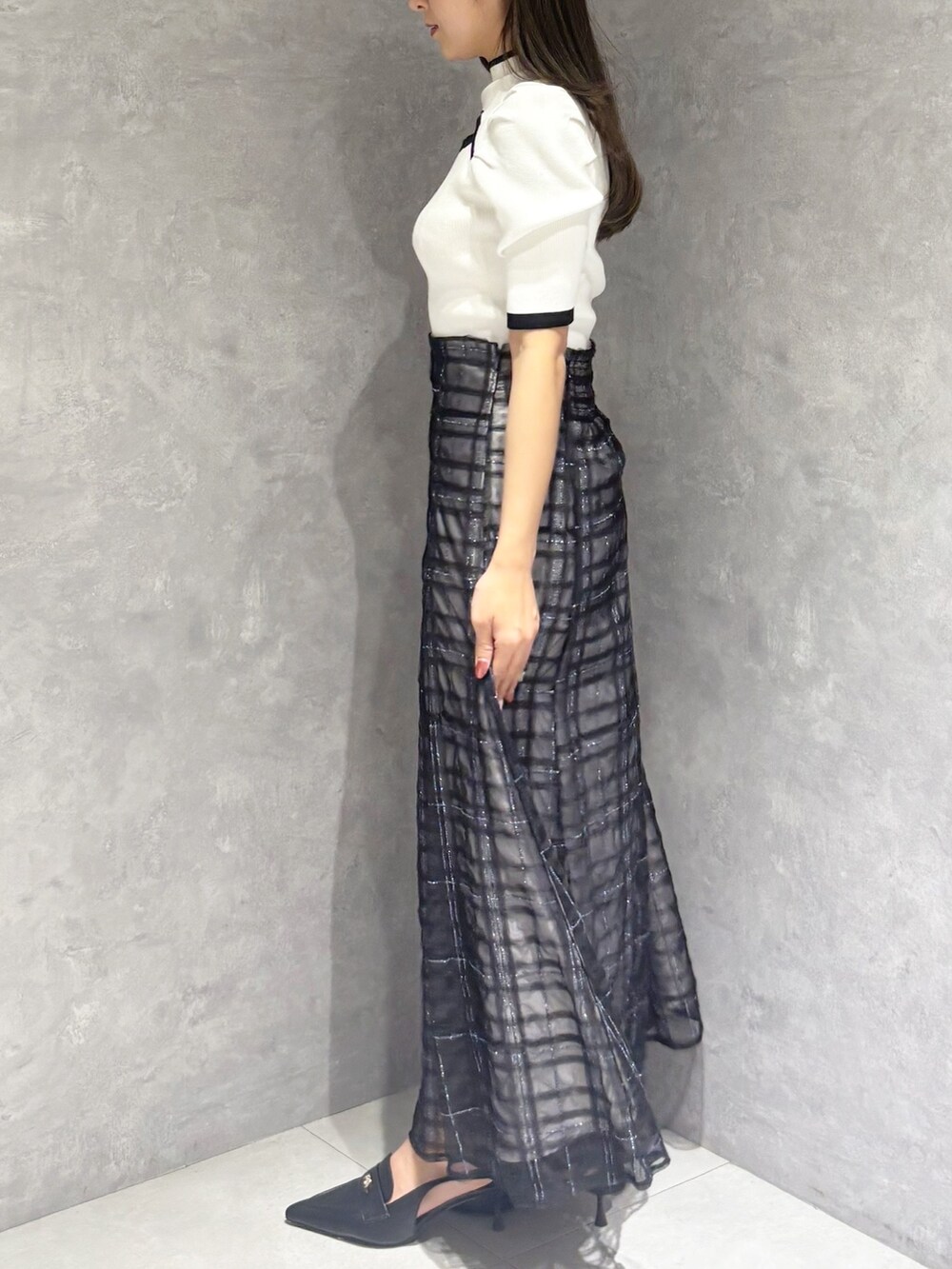 ブルー系のスカート、ブラック系のパンプス、ホワイト系のハンドバッグを着用したレディースの春コーディネートの6枚目の写真