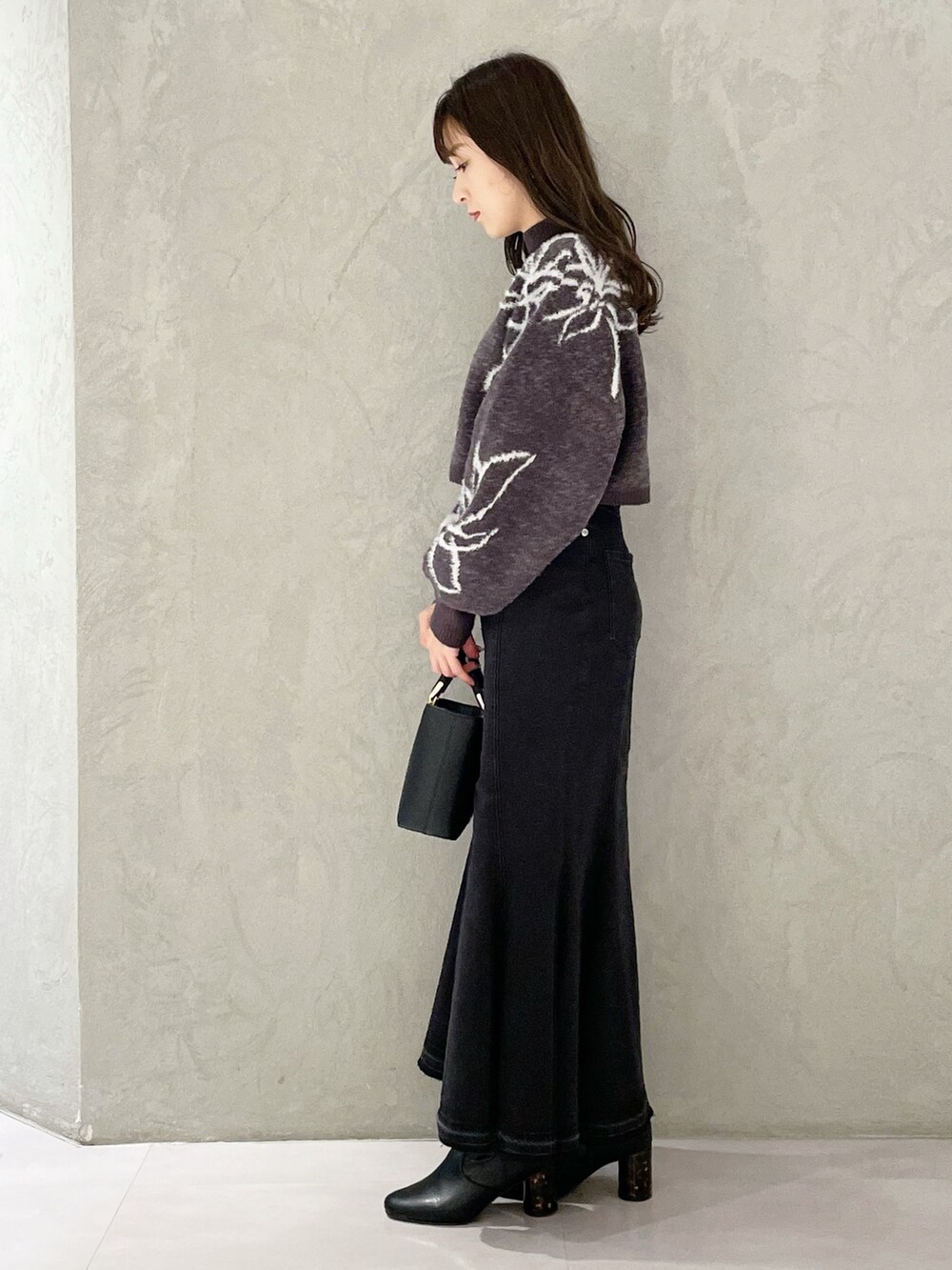 ブラック系のハンドバッグ、ブラック系のスカート、グレー系のニット/セーターを着用したレディースの秋コーディネートの5枚目の写真