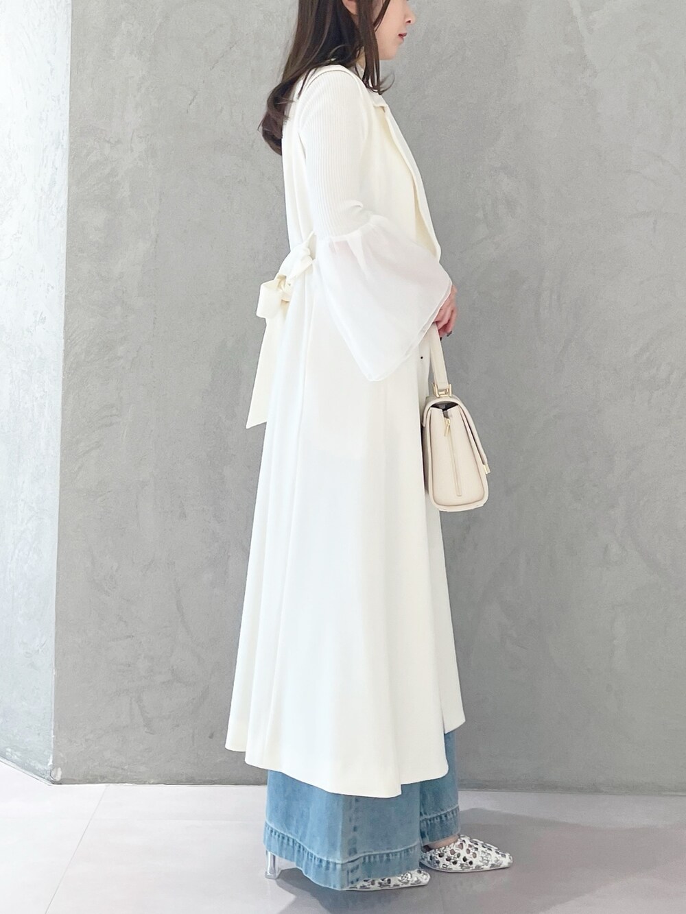 ブルー系のデニムパンツ、ホワイト系のショルダーバッグ、ホワイト系のニット/セーターを着用したレディースの冬コーディネートの6枚目の写真