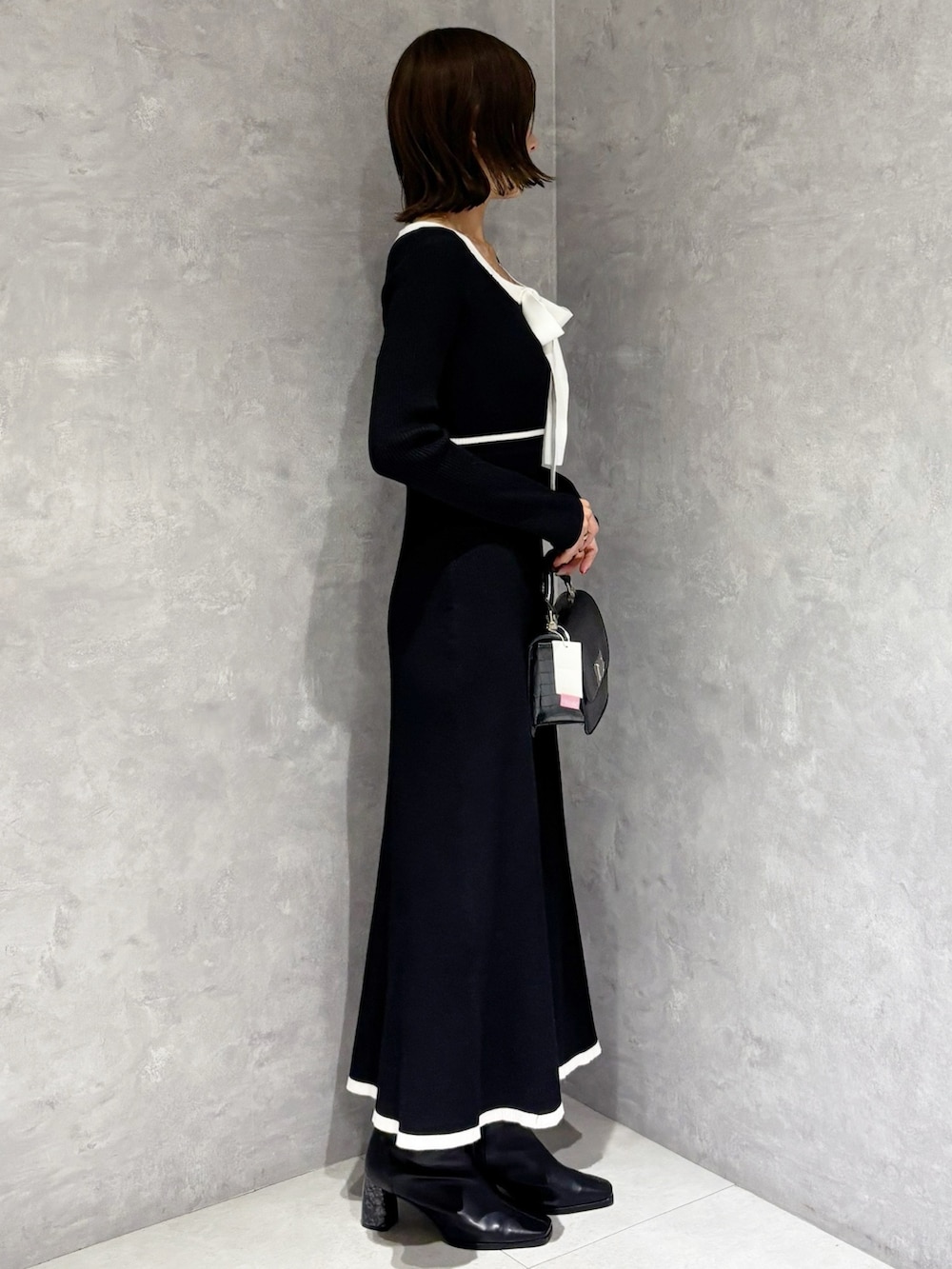 ブラック系のワンピース、ブラック系のハンドバッグ、ブラック系のブーツを着用したレディースの冬コーディネートの4枚目の写真