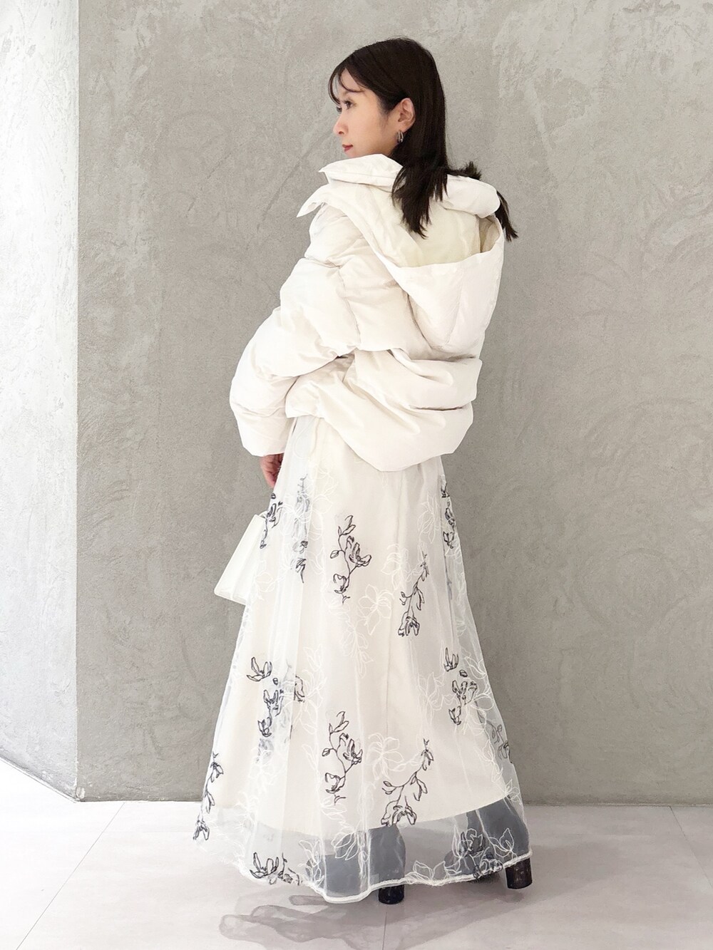 ホワイト系のスカート、ブラック系のブーツ、ホワイト系のハンドバッグを着用したレディースの冬コーディネートの4枚目の写真