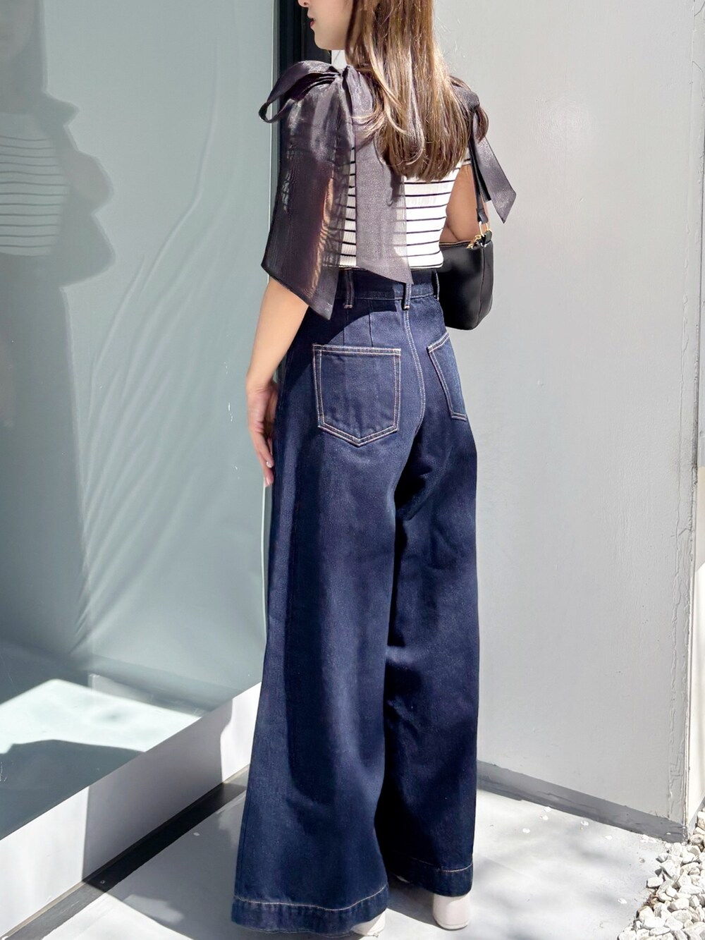 ブルー系のデニムパンツ、その他のニット/セーター、ホワイト系のサンダルを着用したレディースの夏コーディネートの6枚目の写真