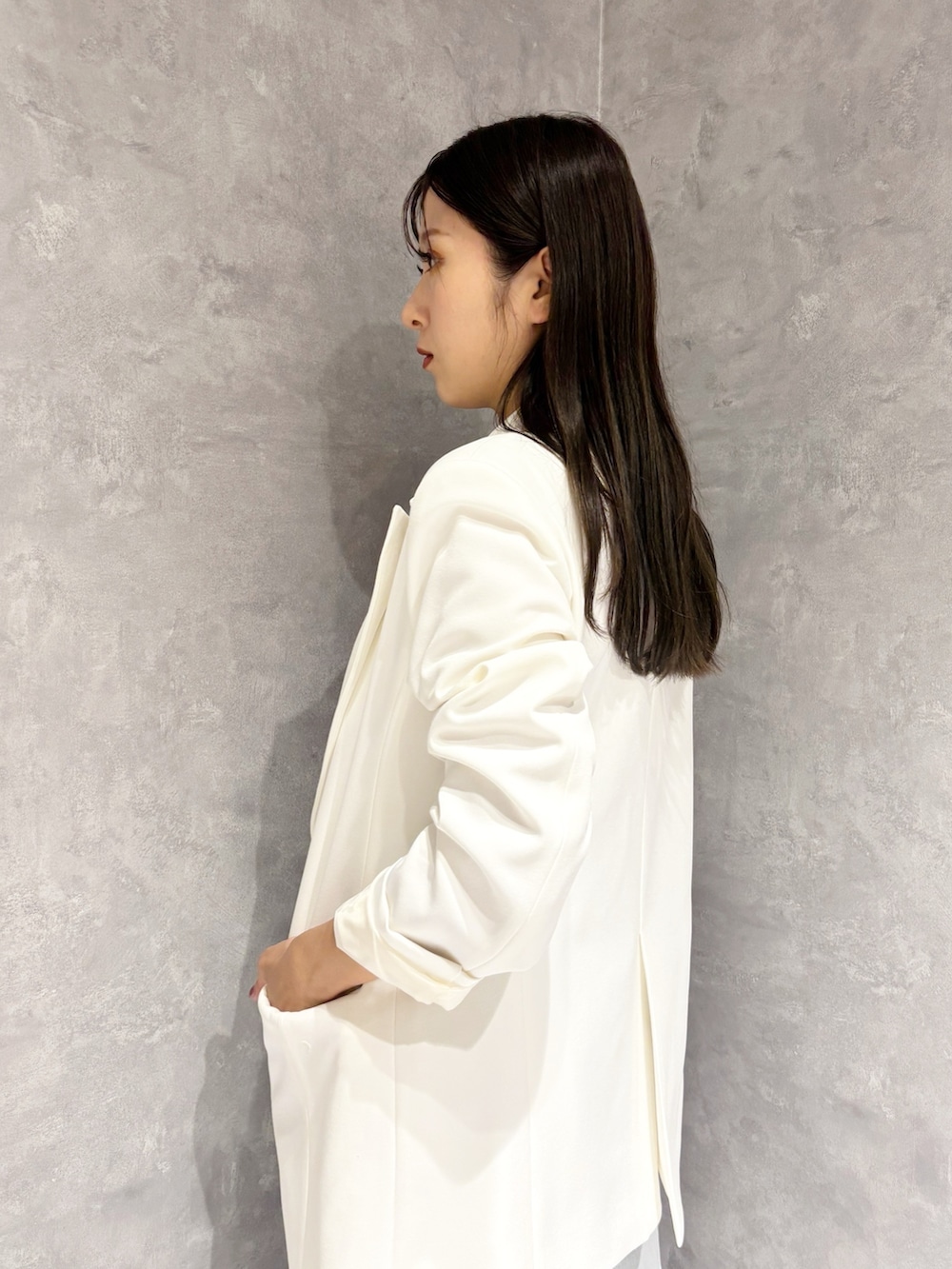 ブルー系のデニムパンツ、ホワイト系のパンプス、ホワイト系のハンドバッグを着用したレディースの冬コーディネートの2枚目の写真