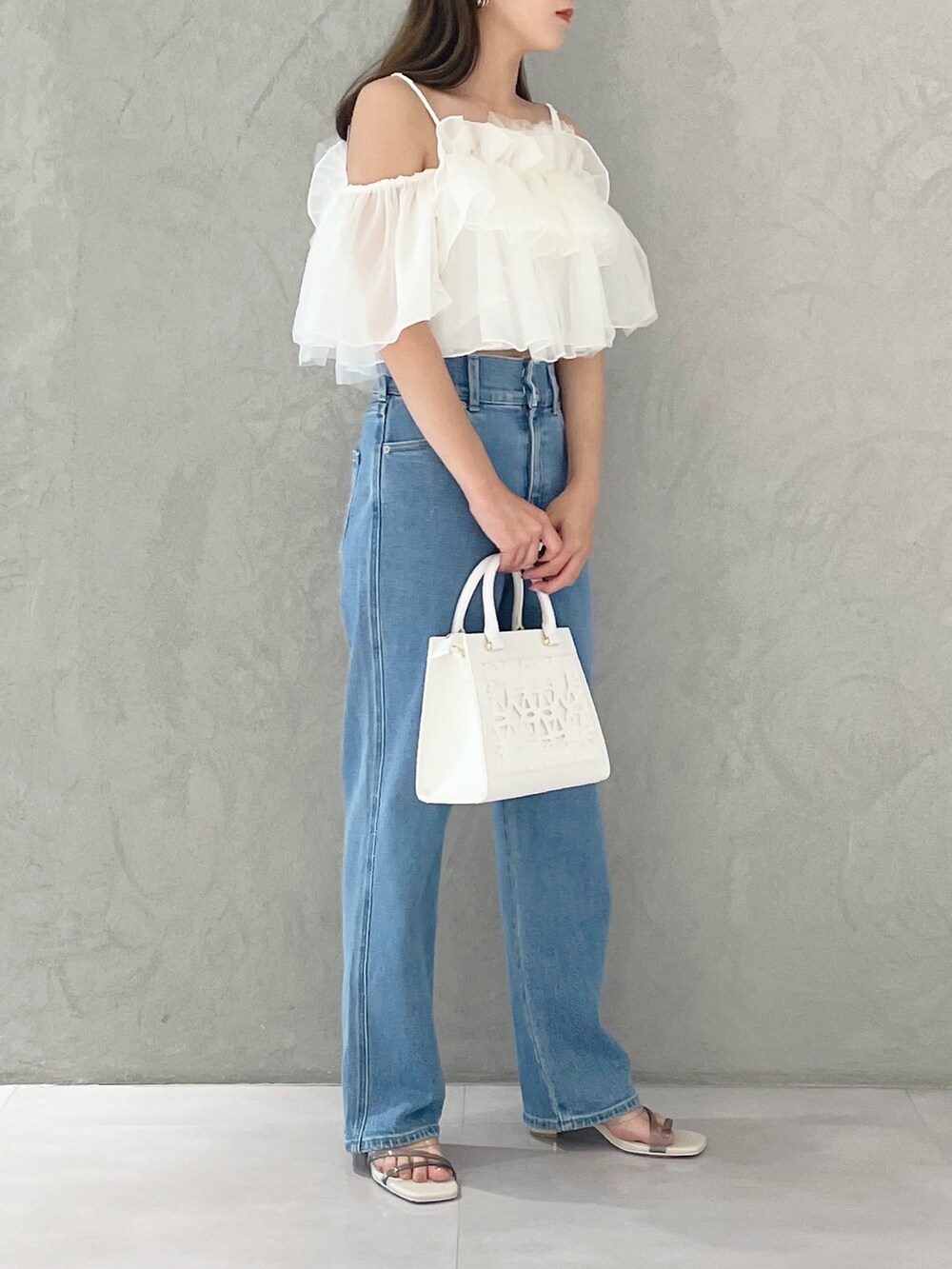 ブルー系のデニムパンツ、ホワイト系のショルダーバッグ、ホワイト系のサンダルを着用したレディースの夏コーディネートの4枚目の写真