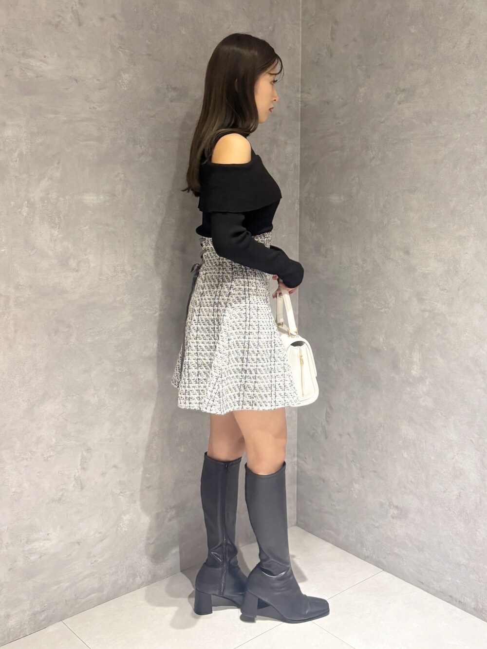 ブラック系のブーツ、ホワイト系のハンドバッグ、ブラック系のニット/セーターを着用したレディースの冬コーディネートの5枚目の写真