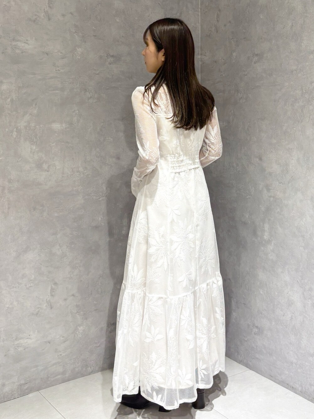 ホワイト系のワンピース、ブラウン系のハンドバッグ、ブラウン系のブーツを着用したレディースの冬コーディネートの3枚目の写真