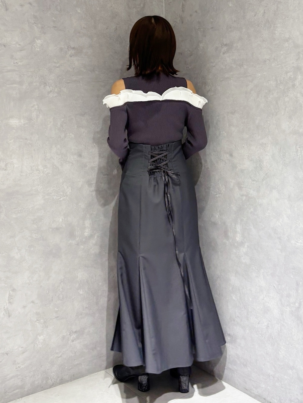 グレー系のスカート、グレー系のニット/セーター、ブラック系のブーツを着用したレディースの冬コーディネートの3枚目の写真