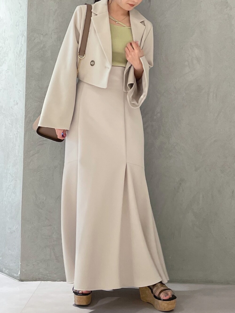 ブラック系のサンダル、ベージュ系のスカート、イエロー系のニット/セーターを着用したレディースの春コーディネートの3枚目の写真