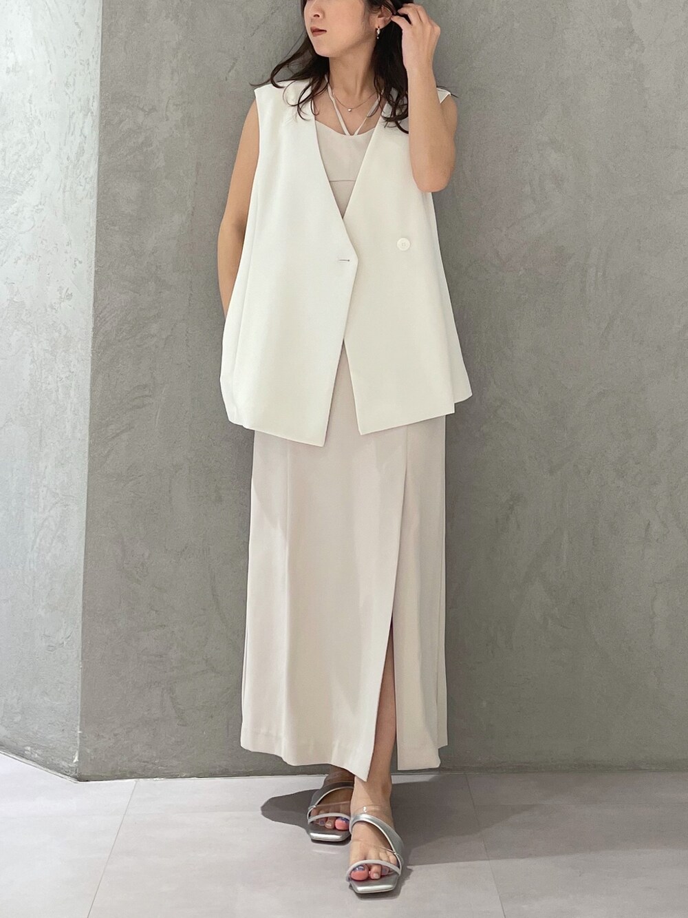 ホワイト系のワンピース、シルバー系のサンダル、ホワイト系のベストを着用したレディースの春コーディネートの5枚目の写真