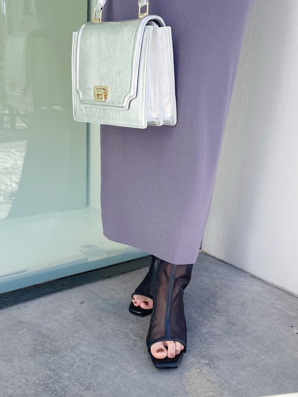 シルバー系のハンドバッグ、ブラック系のブーツ、ブルー系のワンピースを着用したレディースの春コーディネートの3枚目の写真