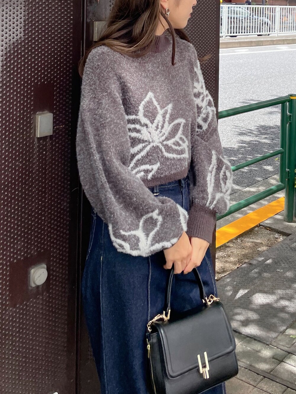 ブラック系のショルダーバッグ、グレー系のニット/セーター、ブルー系のデニムパンツを着用したレディースの秋コーディネートの2枚目の写真