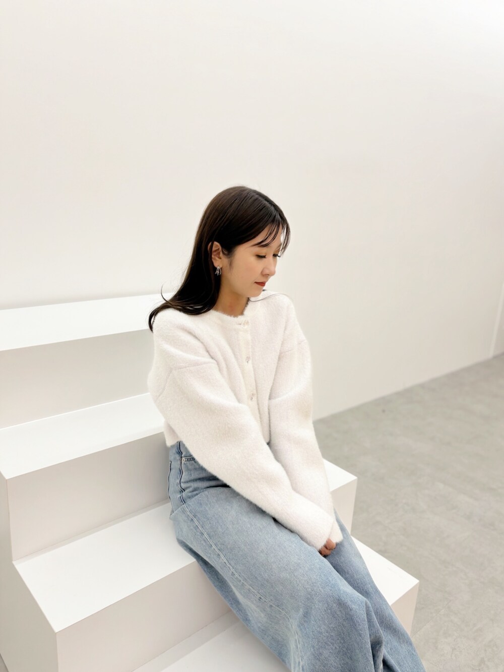 ブルー系のデニムパンツ、ブラック系のブーツ、ホワイト系のカーディガン/ボレロを着用したレディースの秋コーディネートの8枚目の写真