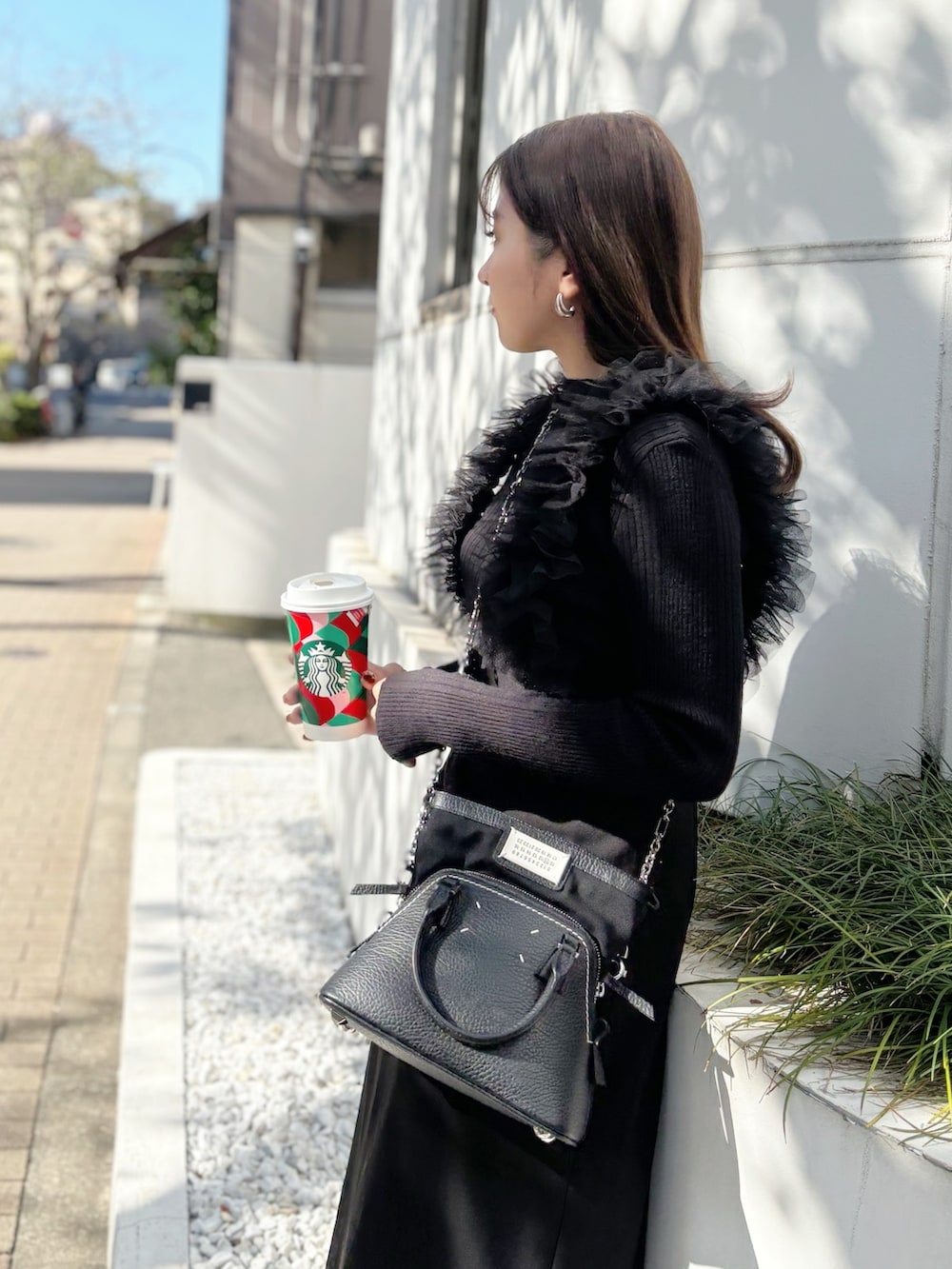 ブラック系のスカート、ブラック系のスニーカー、グレー系のニット/セーターを着用したレディースの秋コーディネートの3枚目の写真