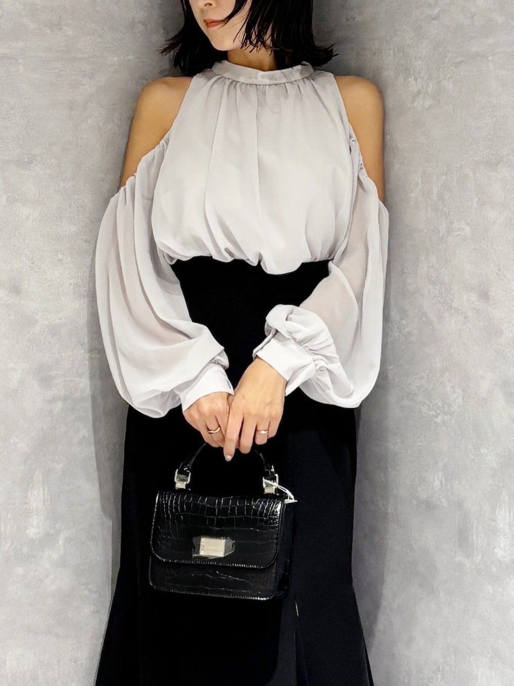 ブラック系のハンドバッグ、ブラック系のブーツ、ブラック系のスカートを着用したレディースの秋コーディネートの7枚目の写真