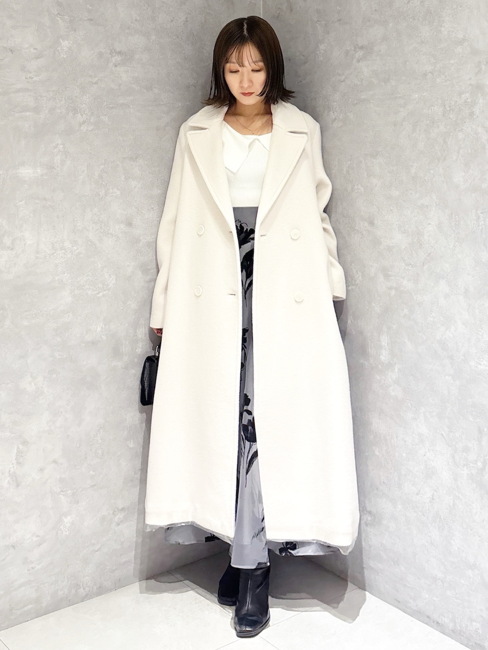 ホワイト系のチェスターコート、ブラック系のブーツ、ホワイト系のニット/セーターを着用したレディースの冬コーディネートの4枚目の写真