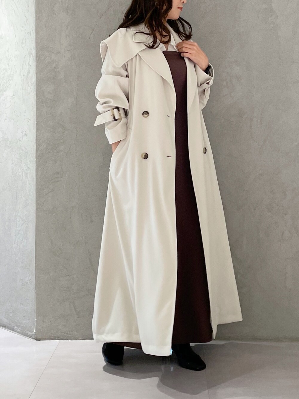 パープル系のワンピース、ブラック系のブーツ、ホワイト系のトレンチコートを着用したレディースの冬コーディネートの6枚目の写真