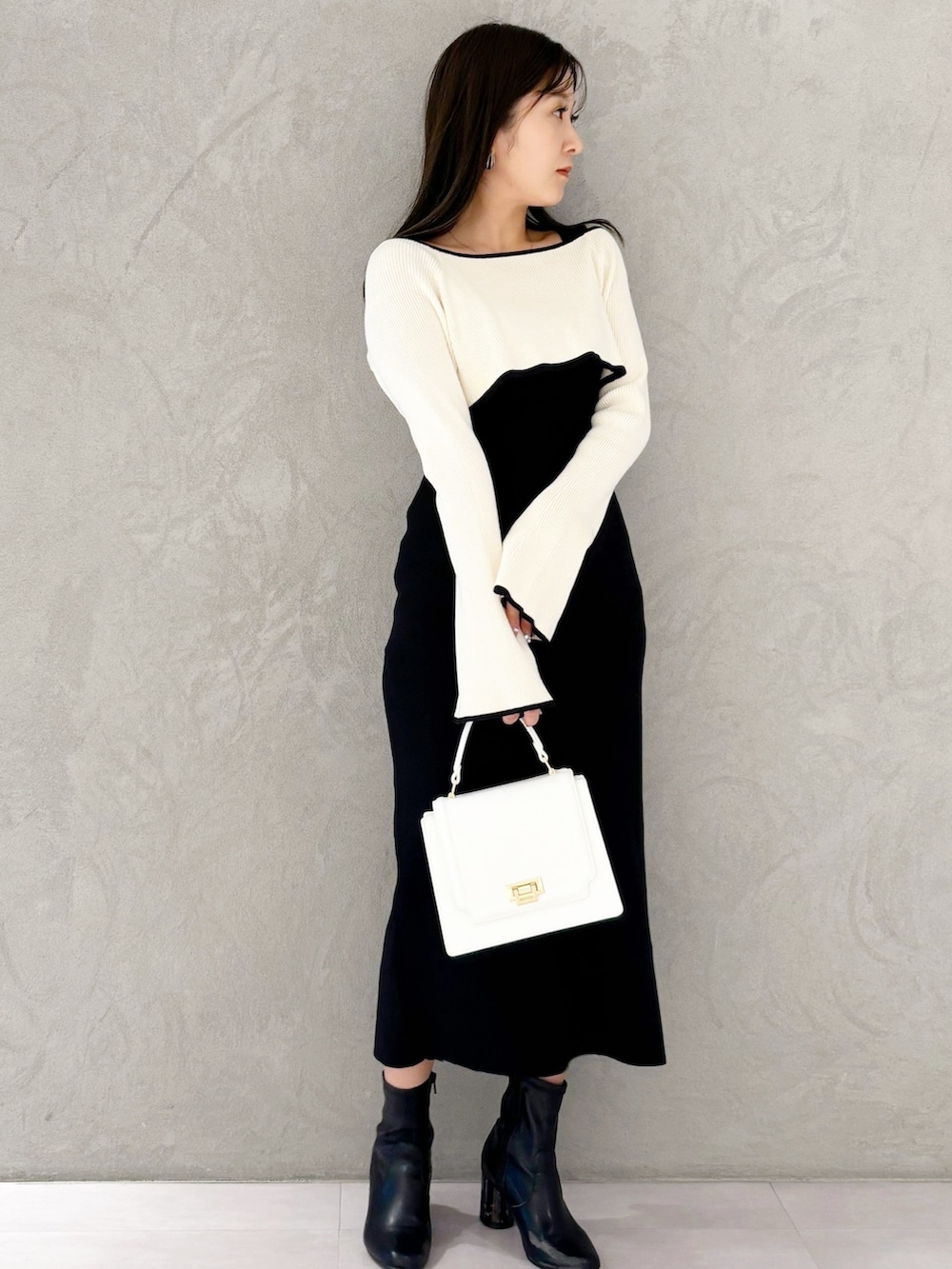 ブラック系のブーツ、ホワイト系のハンドバッグ、ブラック系のワンピースを着用したレディースの冬コーディネートの4枚目の写真