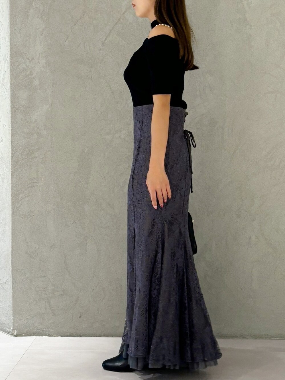 グレー系のスカート、ブラック系のブーツ、ブラック系のショルダーバッグを着用したレディースの秋コーディネートの5枚目の写真