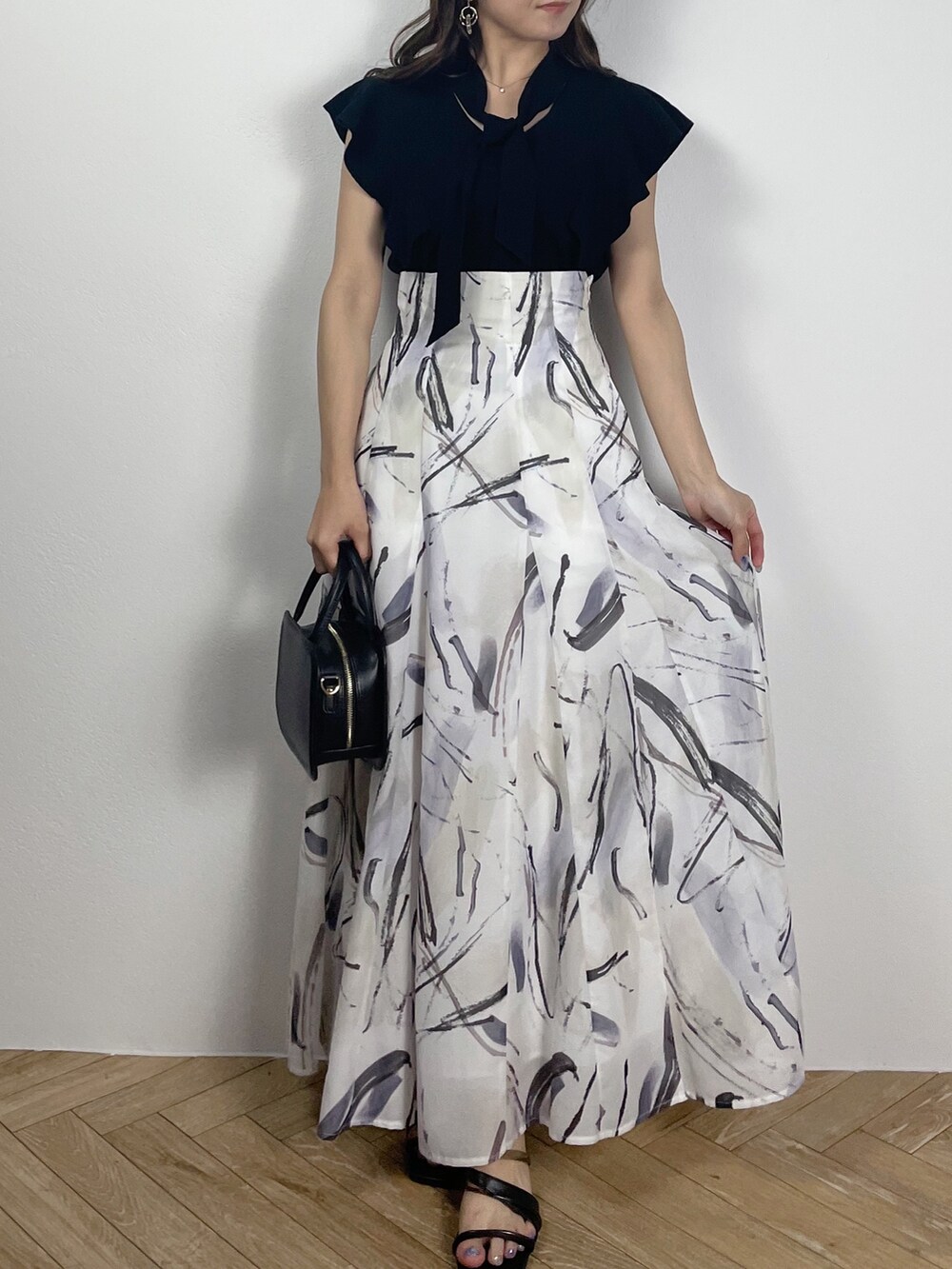 ブラック系のサンダル、ブラック系のニット/セーター、グレー系のスカートを着用したレディースの春コーディネートの4枚目の写真