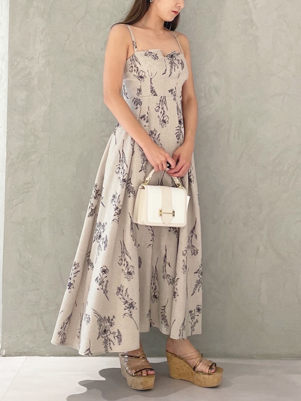ベージュ系のワンピース、ブラウン系のサンダル、ホワイト系のハンドバッグを着用したレディースの夏コーディネートの2枚目の写真
