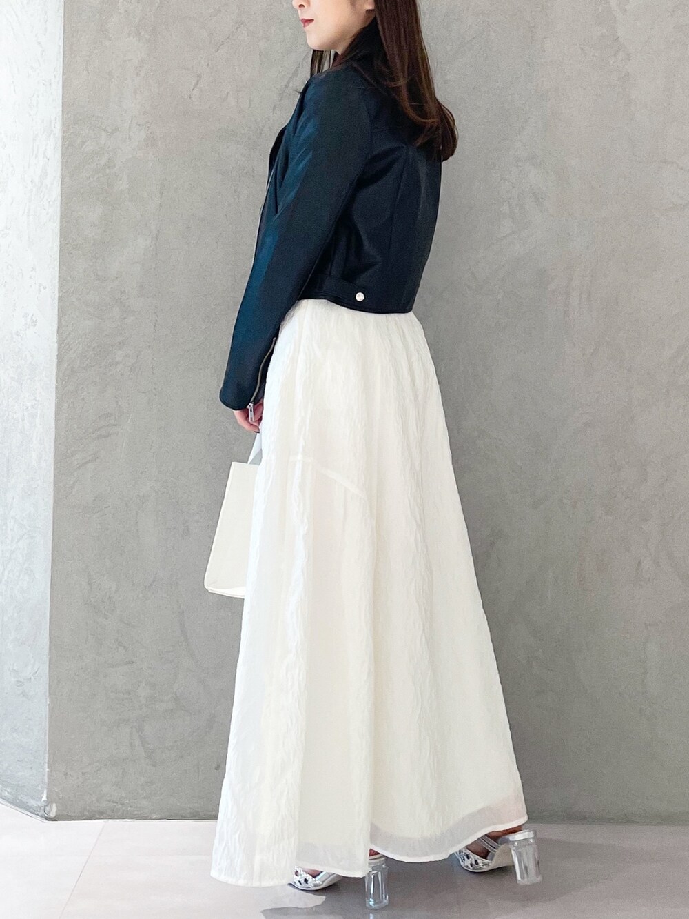 シルバー系のパンプス、ホワイト系のトートバッグ、ブラック系のライダースジャケットを着用したレディースの春コーディネートの4枚目の写真