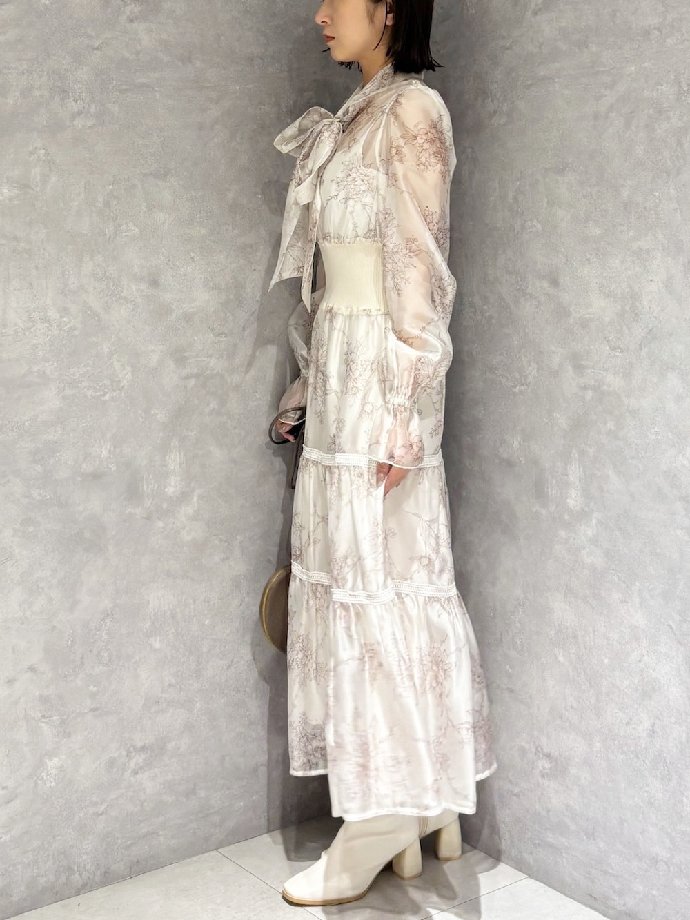 ベージュ系のショルダーバッグ、ホワイト系のブーツ、ベージュ系のワンピースを着用したレディースの冬コーディネートの4枚目の写真